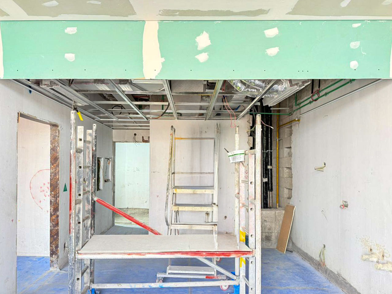 Beach Walk Iii By Imtiaz A construction site with unfinished walls, scaffolding, and a ladder in a spacious interior.